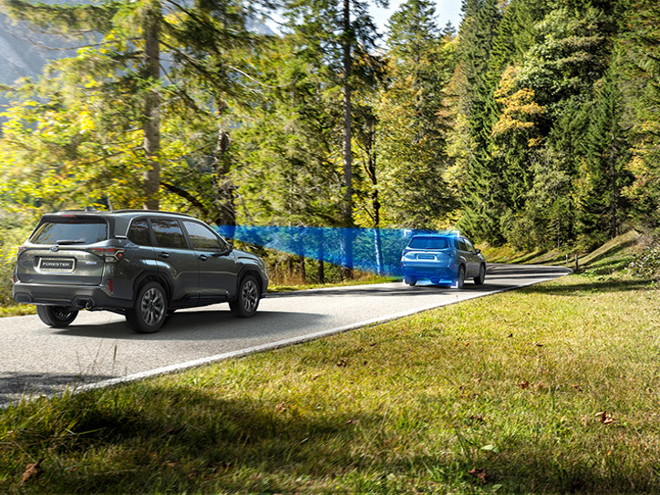 Subaru Forester kører på en vej, med en blå trekantet illustration, der viser synsfeltet fra bilens EyeSight-kameraer.