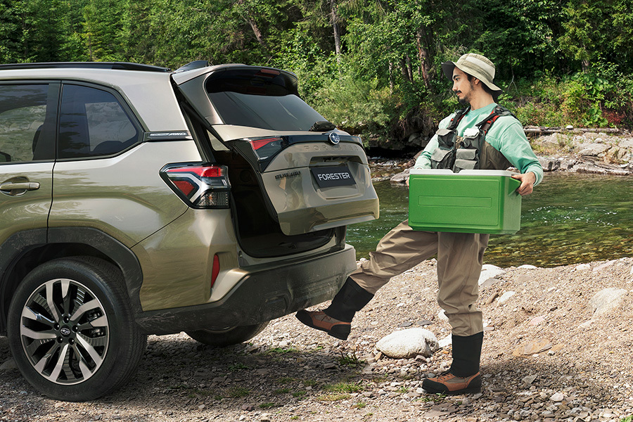 Subaru med håndfri åbning af bagklappen – en mand i fiskeudstyr aktiverer sensoren med foden for at få adgang til bagagerummet uden at bruge hænderne.
