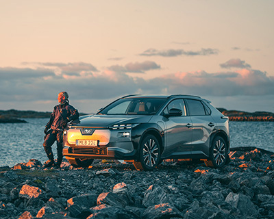 Subaru Solterra parkeret ved havet med en person og dykkerudstyr.