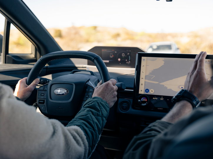 Interiør i Subaru med føreren ved rattet og navigationskort på bilens touchskærm.