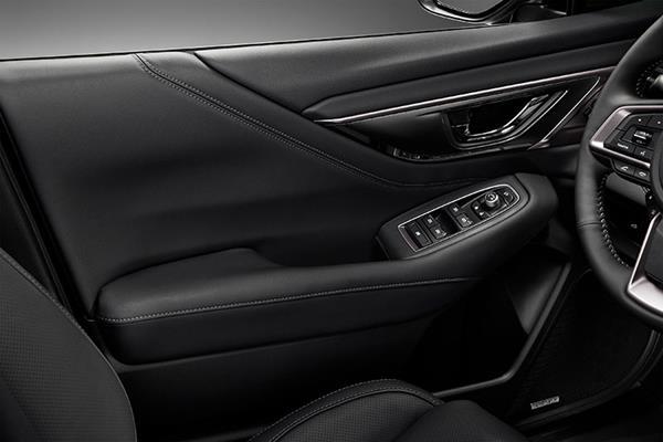 Indersiden af førerdøren i en Subaru med armlæn og knapper til elruder og spejljustering.