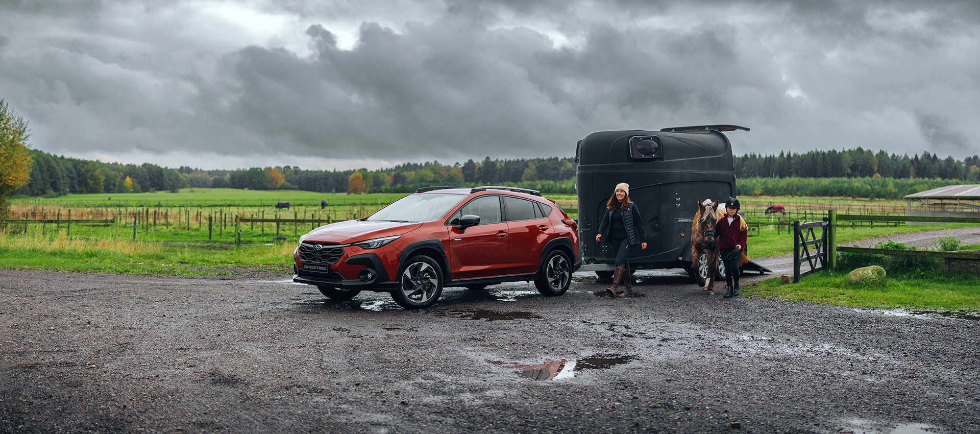 Subaru Crosstrek med hestetrailer i mudret terræn – demonstrerer bilens robuste fremkommelighed og pålidelighed for aktive familier med interesse for heste.